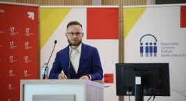 Zdjęcie przedstawia prelegenta na tle slajdu podczas Forum Pomocy Społecznej  